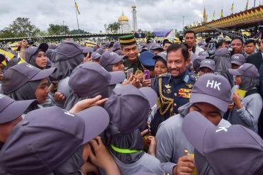 HM the Sultan mingles with students involved in the performances for the 35th National Day celebration. Photo: Infofoto